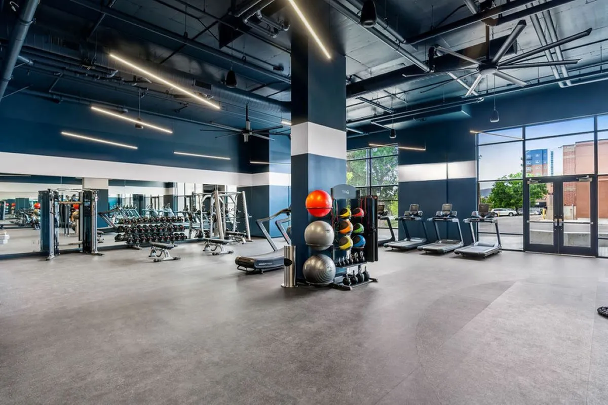 Spacious, modern fitness center equipped with treadmills, free weights, and strength training stations, accented by floor-to-ceiling windows.