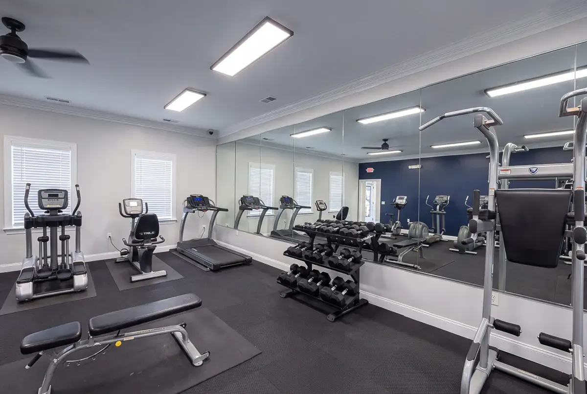 Bright and spacious fitness center featuring modern cardio equipment, mirrored walls, and stylish flooring.