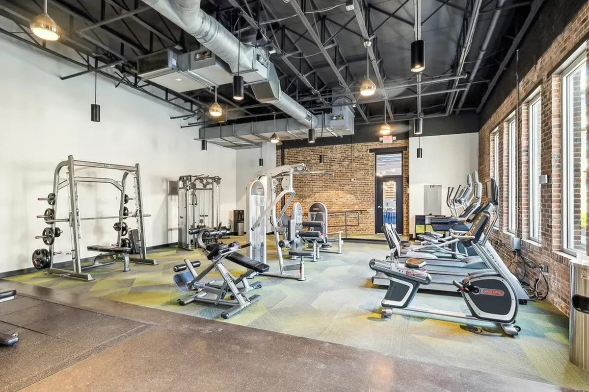 Modern fitness center with state-of-the-art exercise equipment, abundant natural light, and stylish industrial design.