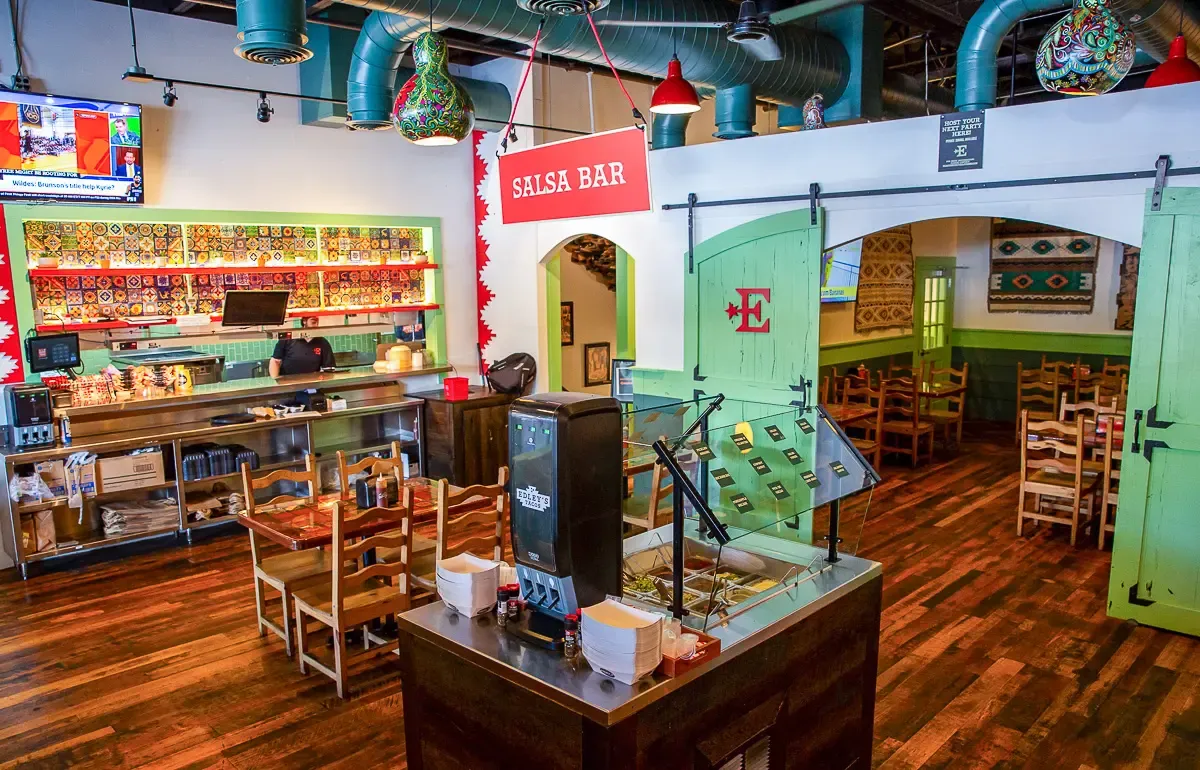 Vibrant restaurant interior featuring a colorful salsa bar, rustic wooden furniture, and lively decor, perfect for a cozy dining experience.
