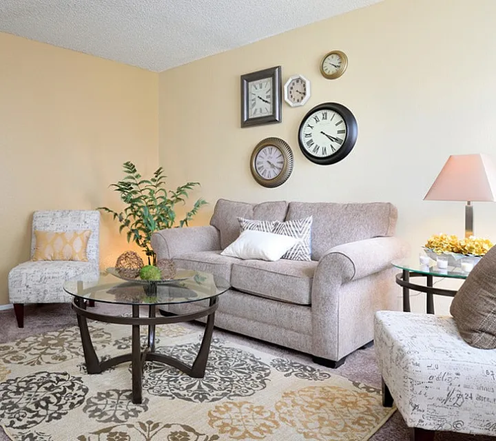 Inviting living room at Camelot Apartments with cozy sofa, modern glass coffee table, and elegant decor in a warm, neutral palette.