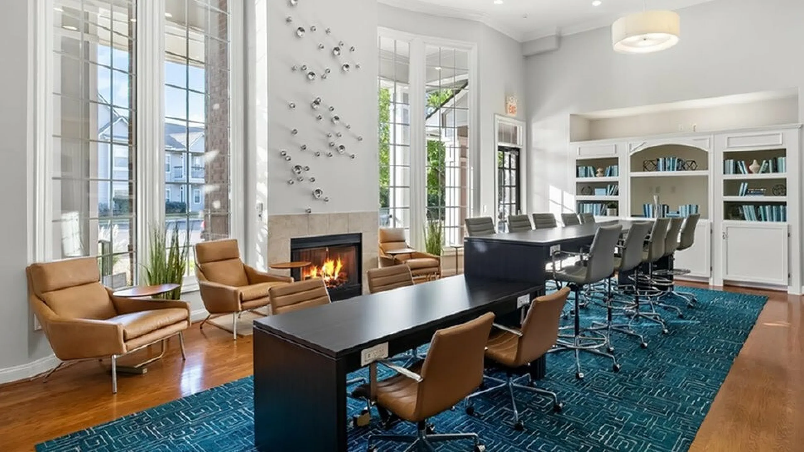 Elegant coworking space at Cason Estates Apartments with modern seating, a cozy fireplace, and large windows offering natural light.