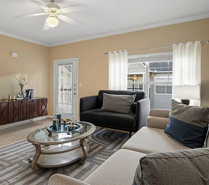 Inviting living room with modern decor featuring plush sofas, elegant coffee table, and a glimpse into a cozy bedroom, perfect for comfortable living.