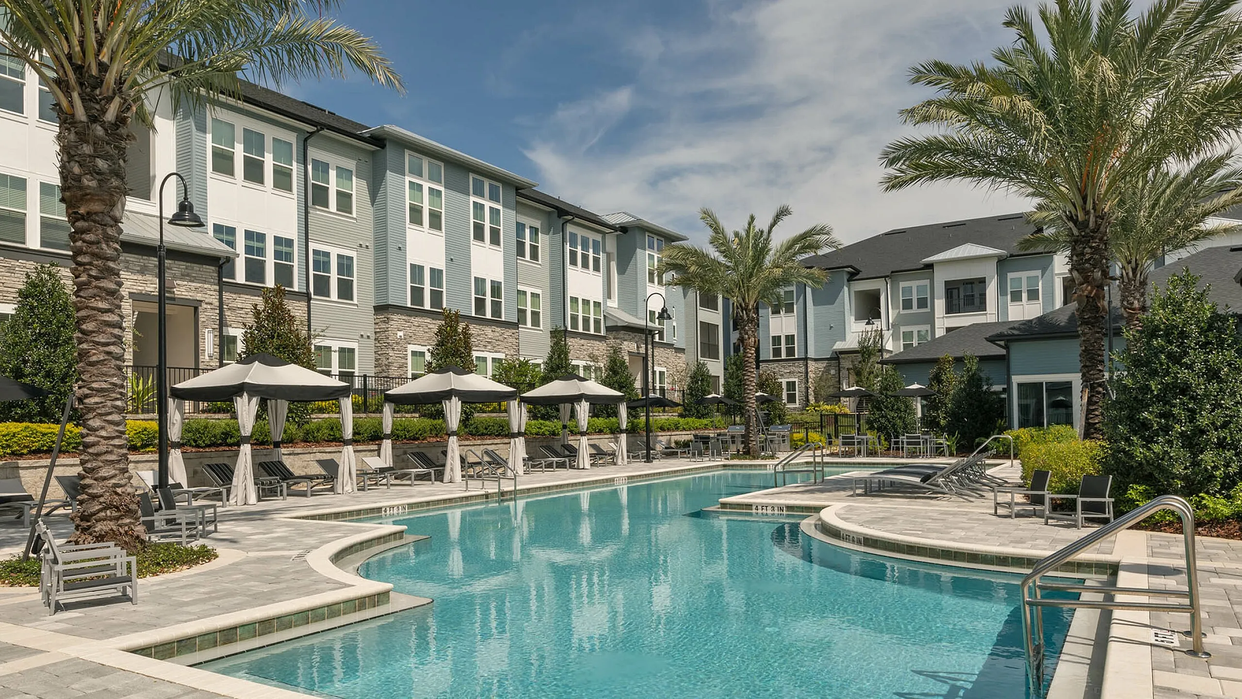 View of Cottonwood Clermont with elegant resort-style pool, surrounded by palm trees and modern architecture, perfect for relaxation and leisure.