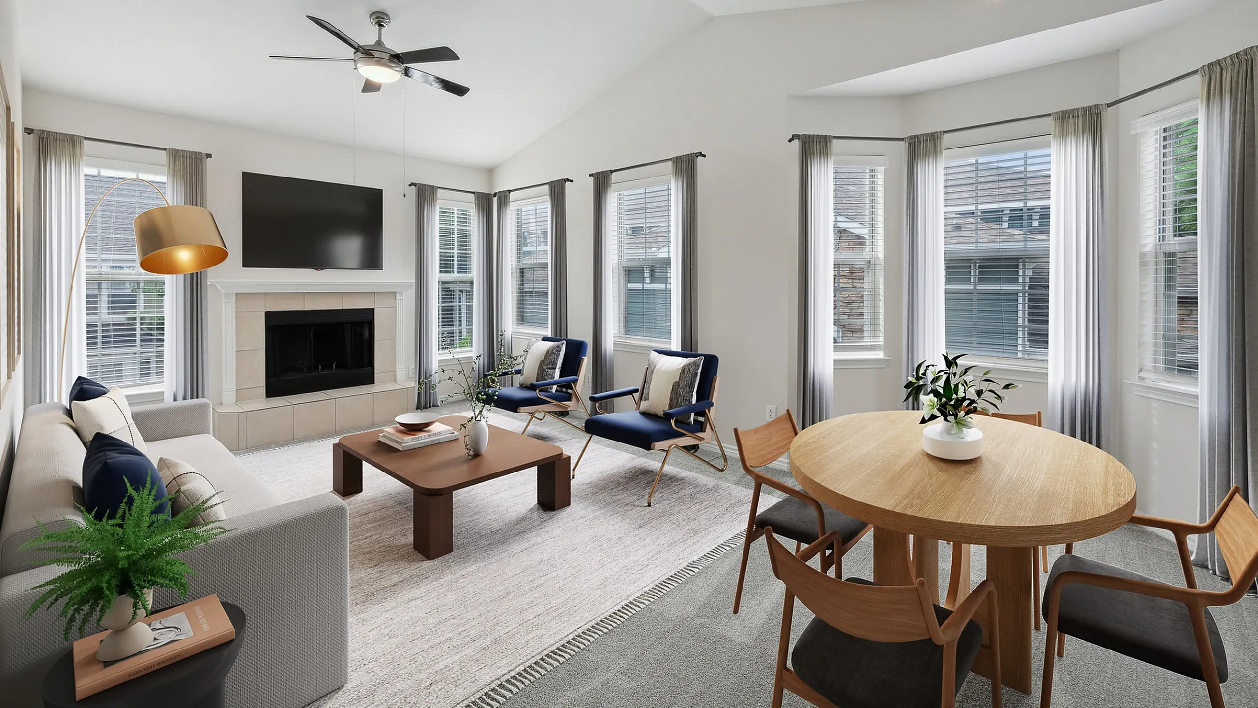 Bright and elegant living room at Cottonwood Ridgeview Apartments with modern furnishings, featuring a cozy fireplace, stylish seating area, and an inviting dining space.