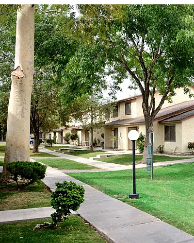 Charming apartment community with lush greenery, palm trees, and well-maintained pathways offering a serene neighborhood vibe at Camelot Apartments in Yuma AZ