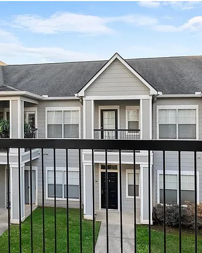 Charming two-story apartment facade with a cozy balcony, lush greenery, and serene courtyard view at Cason Apartments in Murfressboro