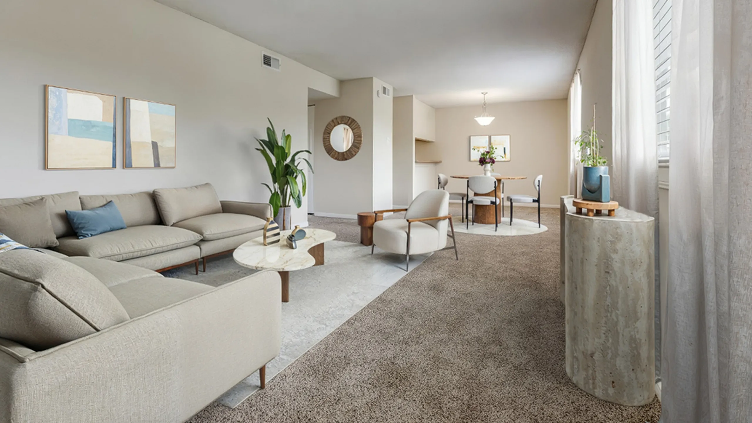 Inviting open-concept living and dining area at Regatta Apartments featuring a cozy beige sofa, elegant decor, and abundant natural light.