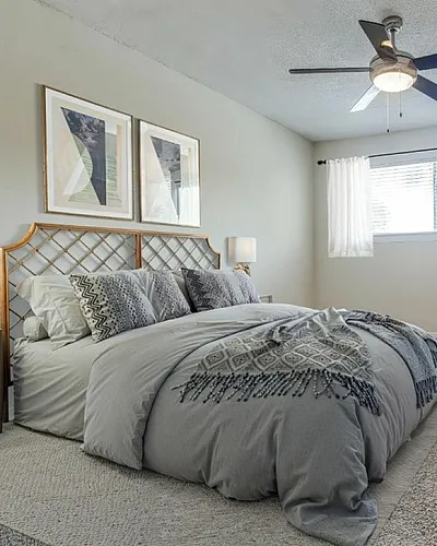 Serene bedroom at Regatta with elegant decor, featuring a cozy bed with stylish bedding, modern ceiling fan, and natural light pouring through large window.