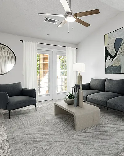 Modern living room with elegant gray sofa, stylish armchair, and contemporary art, illuminated by natural light from glass doors.