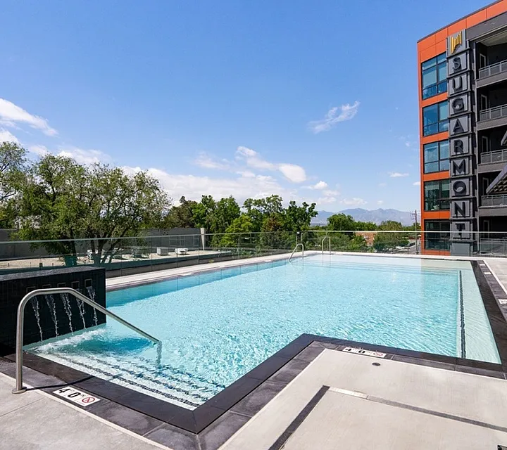 Inviting rooftop pool with modern design and scenic views in front of a stylish apartment complex at Sugarmont Apartments in Sugar House Utah