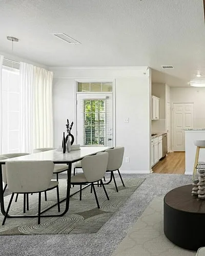 Elegant open-plan living space featuring a modern kitchen with bar stools, cozy sectional sofa, and stylish dining area bathed in natural light.