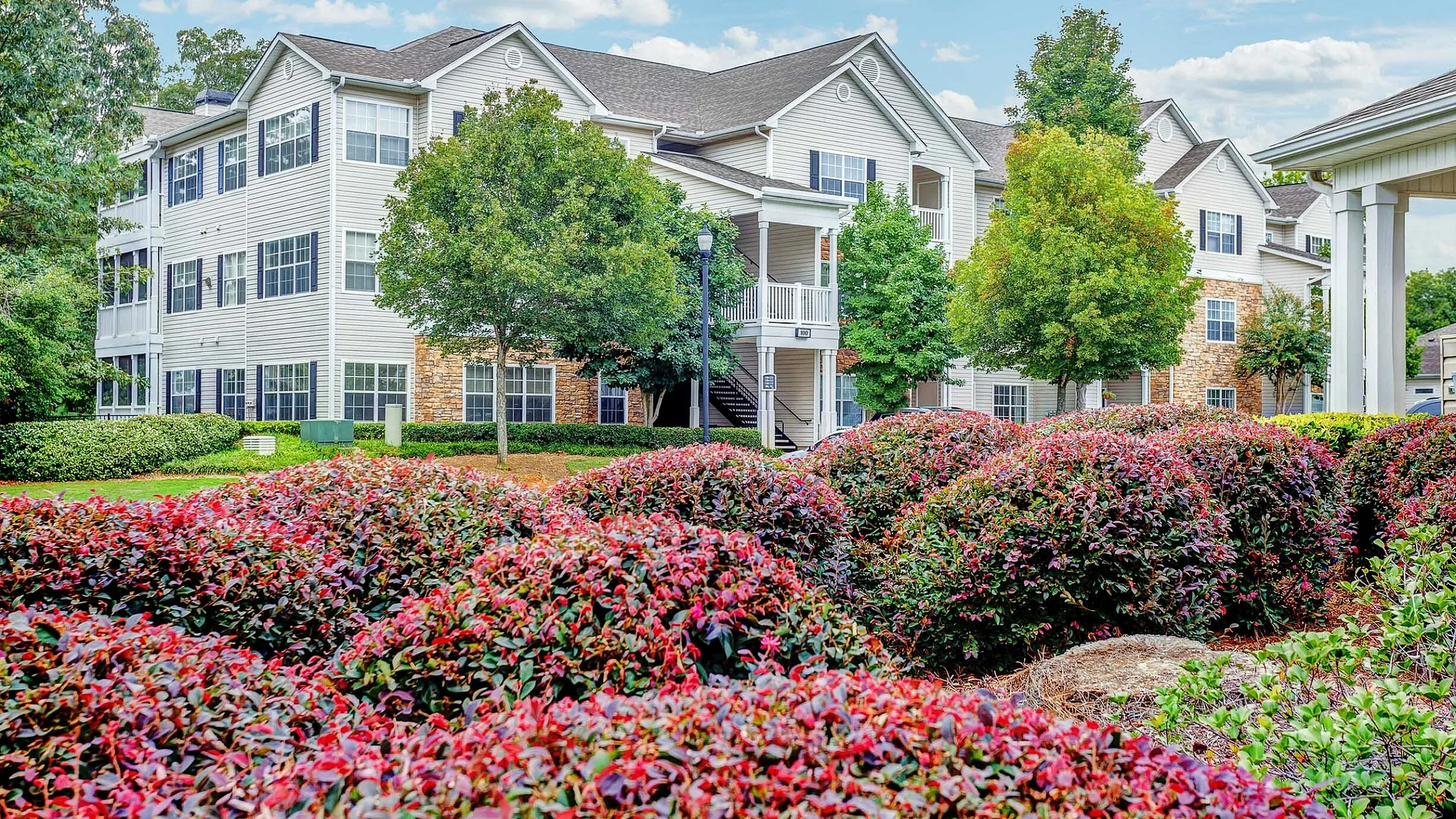 Charming apartment complex with lush landscaping, vibrant foliage, and elegant architecture.