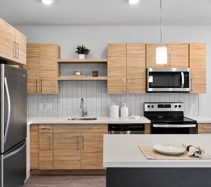 Modern kitchen with sleek stainless steel appliances, warm wooden cabinetry, and elegant pendant lighting.