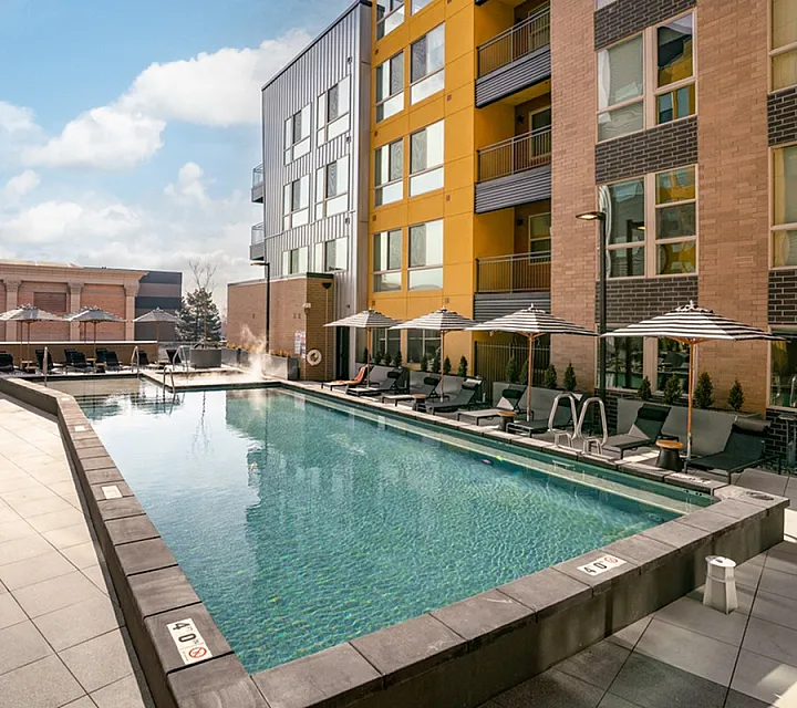 Luxurious apartment complex showcasing a sparkling outdoor swimming pool surrounded by modern loungers and stylish umbrellas, offering a premium leisure experience at Cottonwood Highland in Millcreek UTAH