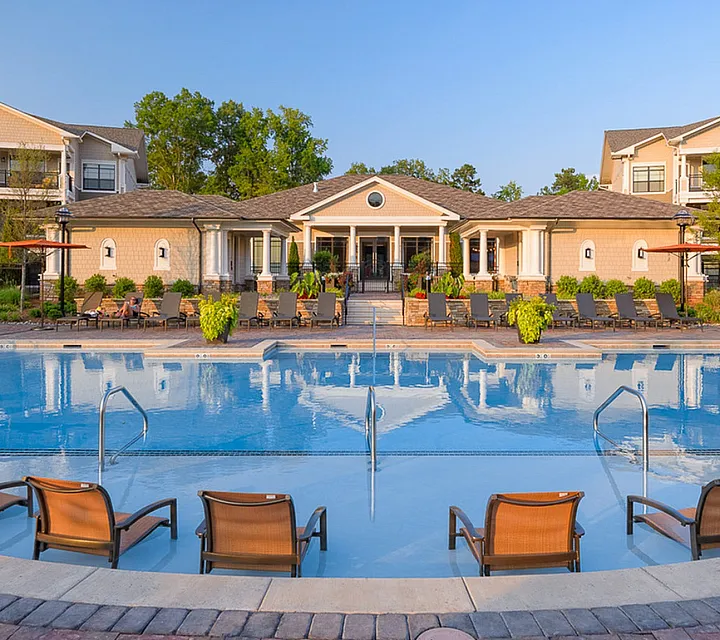 Luxurious apartment complex featuring a stunning outdoor pool and elegant lounge areas, surrounded by lush greenery and modern architecture at Heights at Meridian in Durham NC