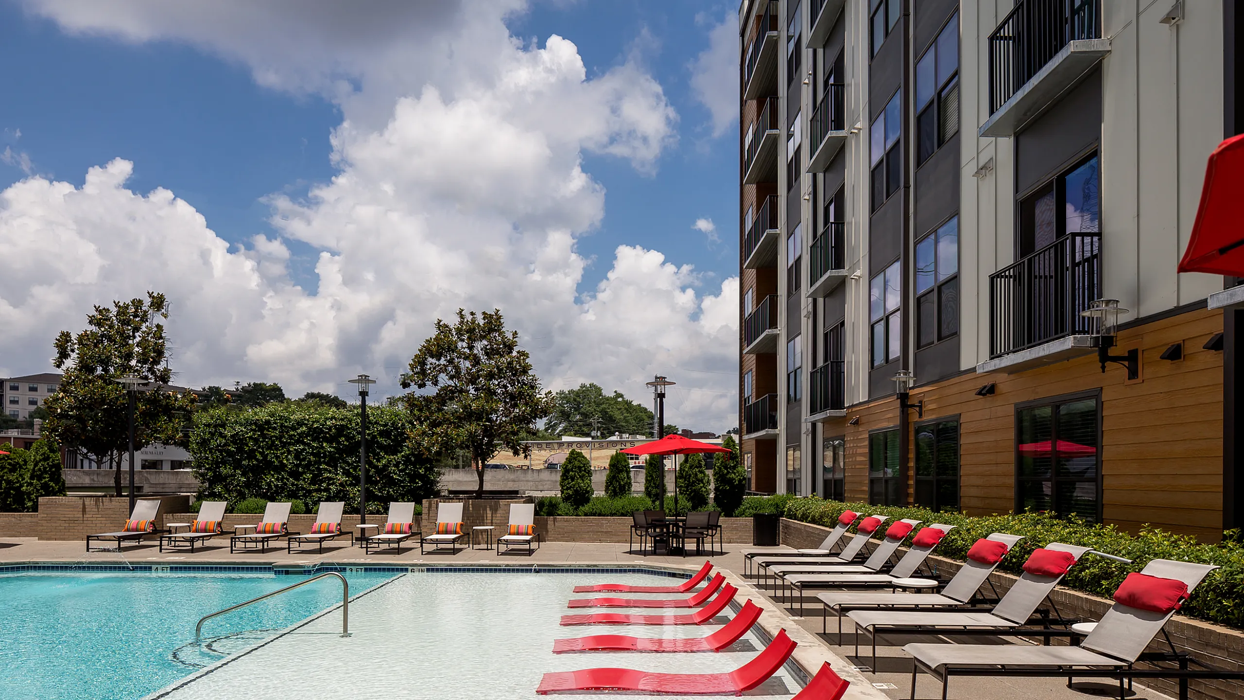 Luxurious apartment community featuring a sparkling pool with red lounge chairs and modern outdoor seating, perfect for relaxation and sunny days Cottonwood Westside Apartments in West Midtown Atlanta