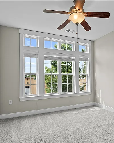 Bright and spacious bedroom with plush carpet and large windows offering abundant natural light at Alpha Mill Apartments in NODA Charlotte