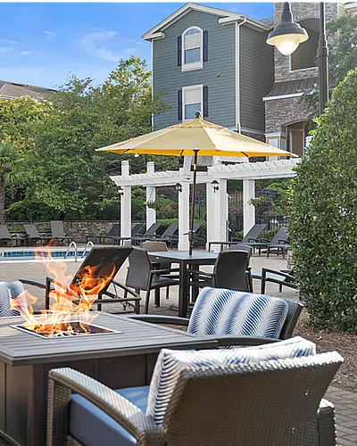 Luxurious apartment community with a sparkling pool, stylish fire pit setup, and comfortable seating, perfect for relaxation and socializing at Cottonwood Reserve Apartments in Steele Creek Charlotte NC