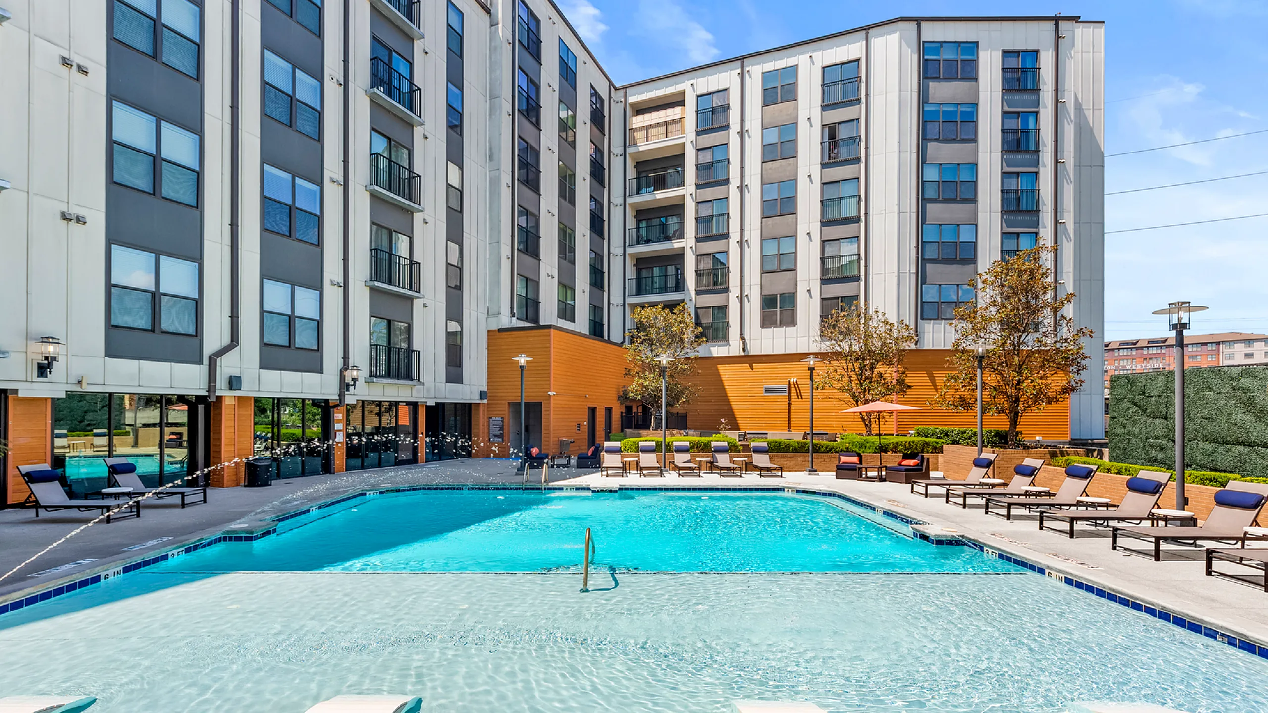 Luxurious apartment complex featuring a sparkling outdoor pool, elegant lounge chairs, and modern architectural design in West Midtown Atlanta GA