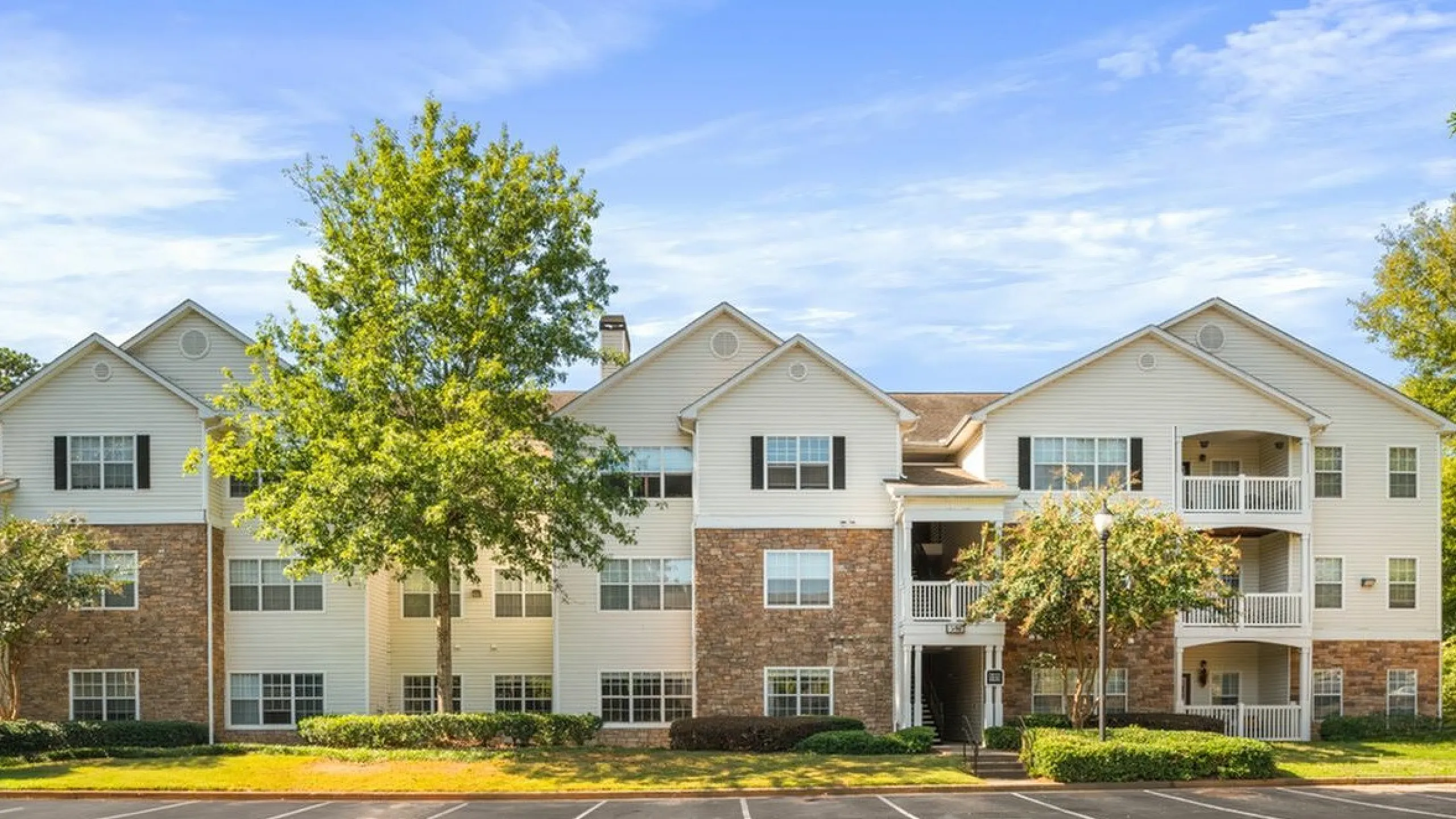 Charming apartment complex with classic architecture, lush landscaping, and spacious balconies perfect for relaxing and enjoying the view at Summer Park Apartments in Buford GA