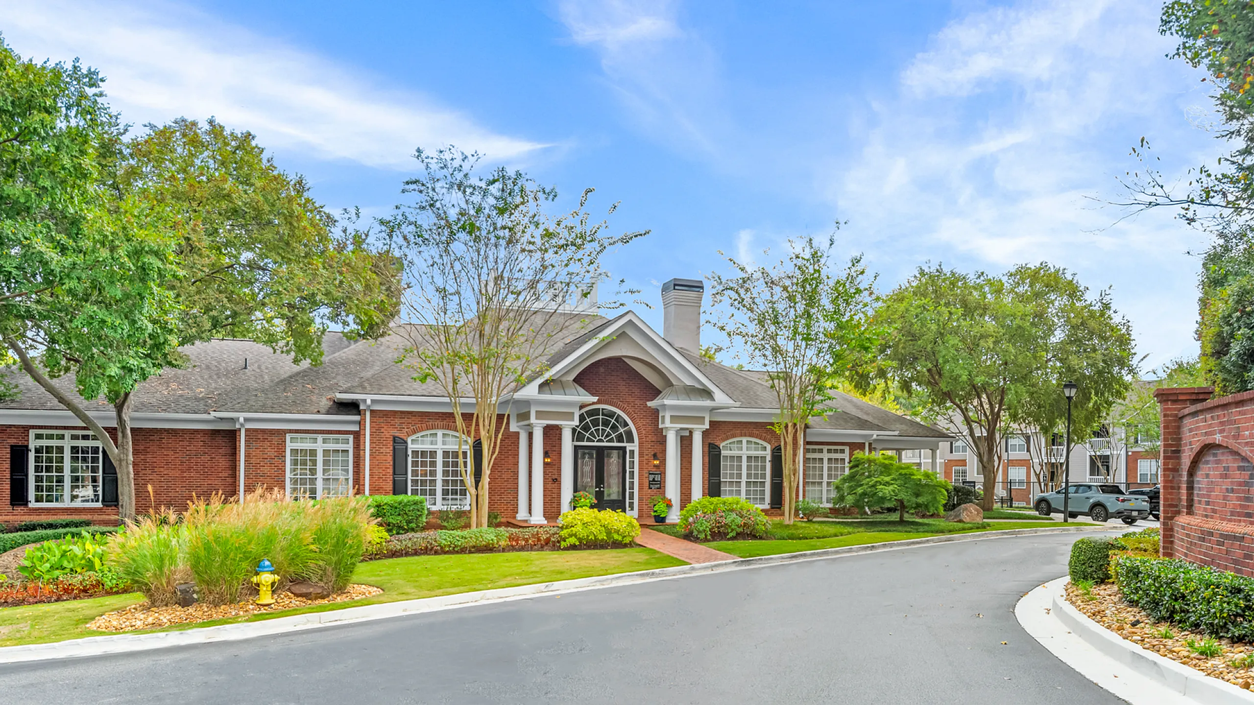 Charming brick building with large arched windows and lush landscaping under a clear blue sky Whether you're enjoying a match on the tennis court or strolling on the on-site walking paths, outdoor fun is always within reach at Retreat