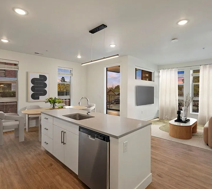 Modern open-concept living space with a sleek kitchen island, cozy dining nook, and a sunlit living room featuring stylish decor at The Richmond Apartments in Millcreek, UT.