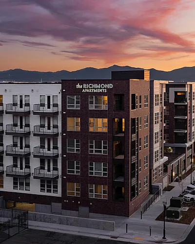 The Richmond Apartments at sunset, showcasing modern architecture with private balconies and a scenic mountain backdrop.