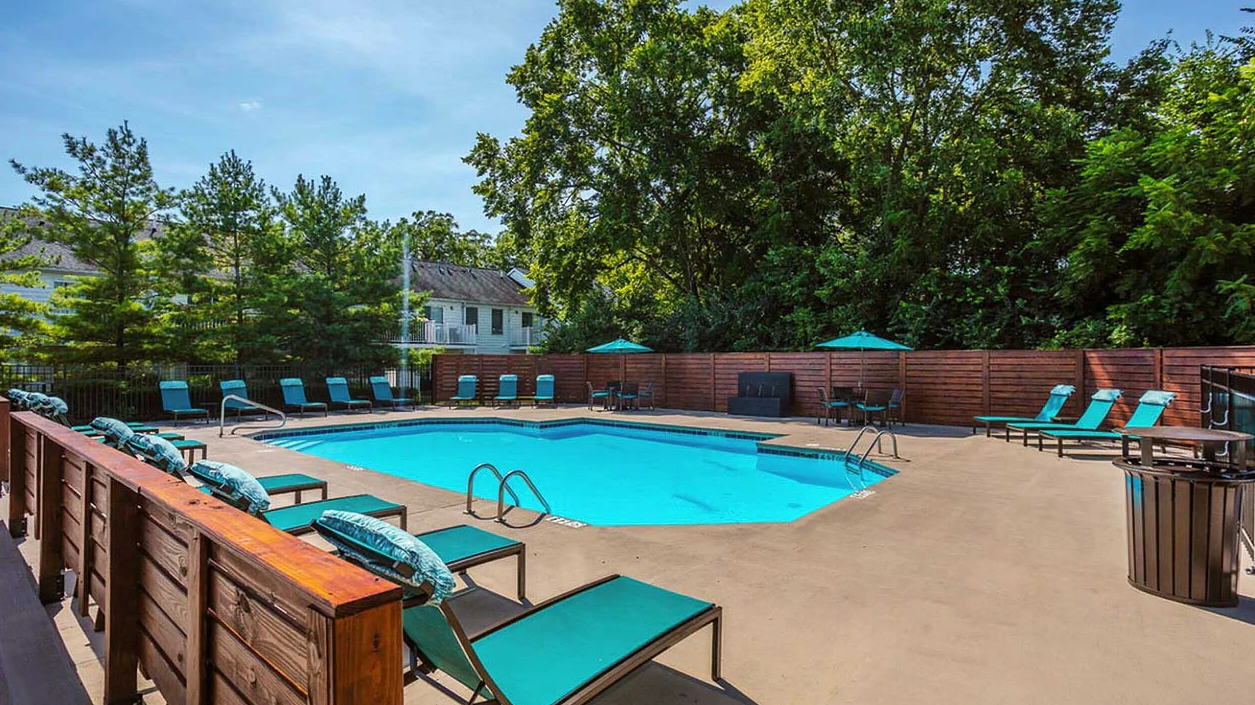 Luxurious outdoor pool area with stylish lounge chairs and vibrant umbrellas, surrounded by lush greenery for a serene oasis experience.