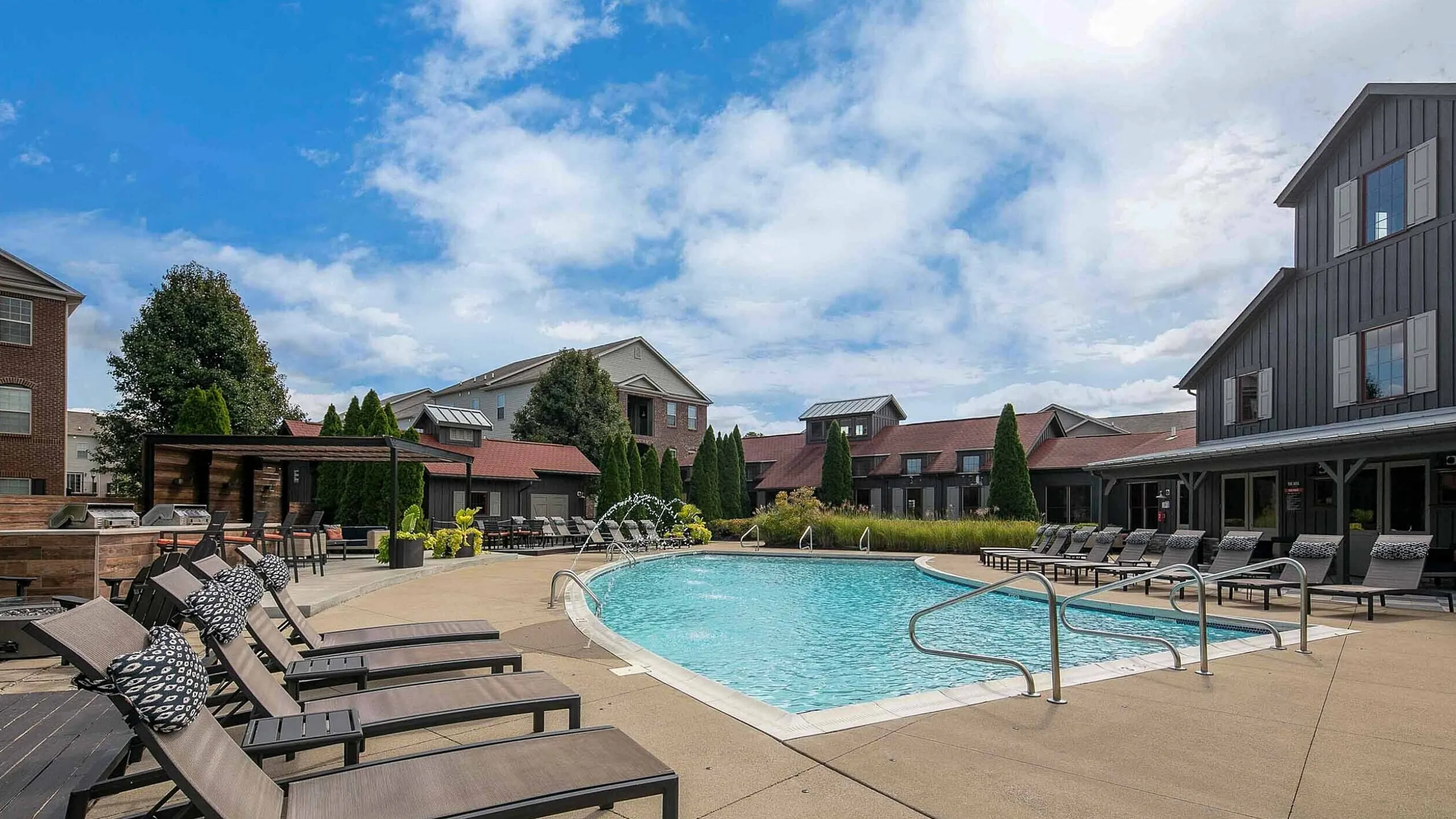 Inviting outdoor pool area with comfortable lounge chairs and elegant landscaping, nestled within a stylish apartment community.