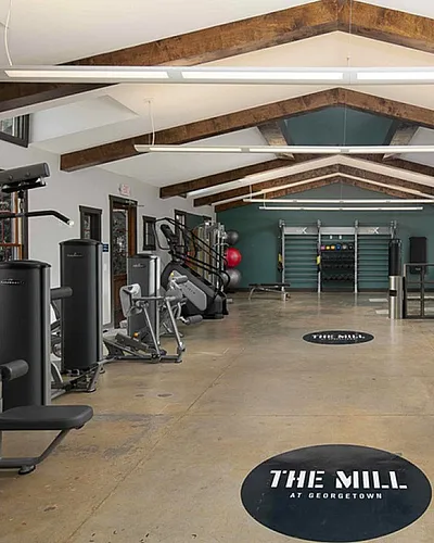 Spacious and modern fitness center at The Mill featuring state-of-the-art exercise equipment and rustic beam ceilings.