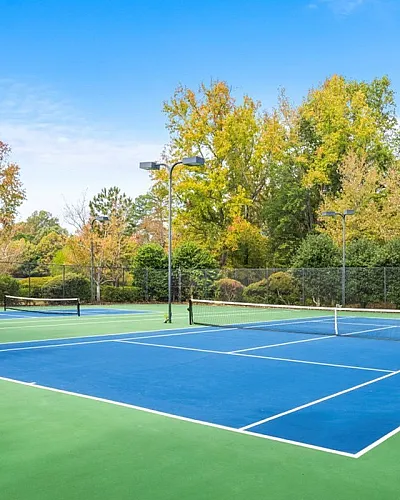 Inviting tennis courts surrounded by lush greenery and modern apartments, perfect for recreation and leisure.