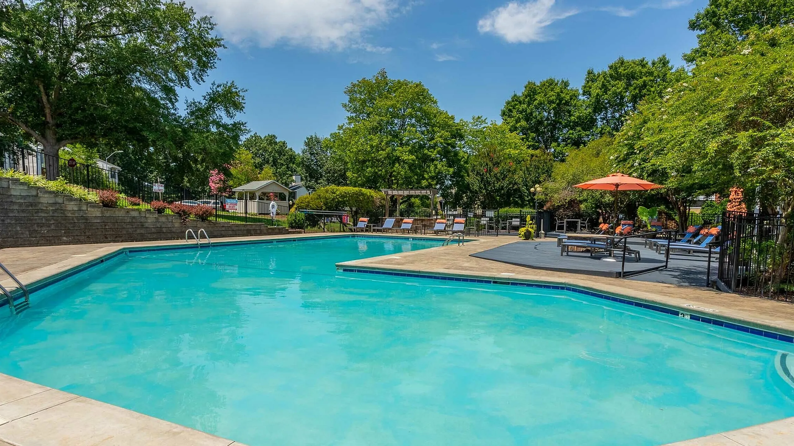 Inviting outdoor swimming pool surrounded by lush greenery and sun loungers, perfect for relaxation and leisure.