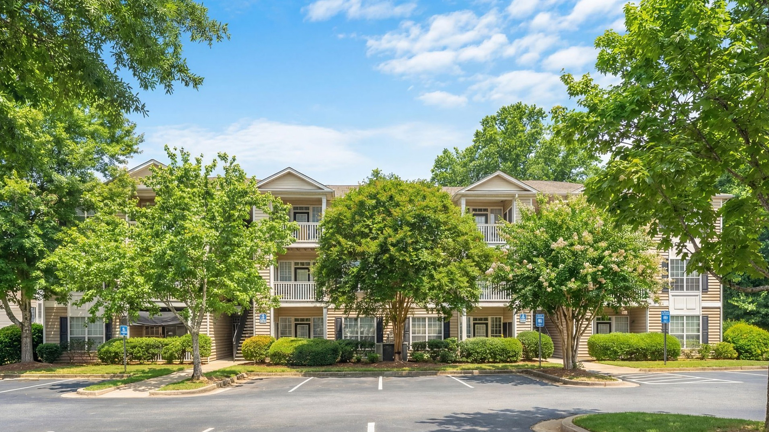 Charming apartment complex surrounded by lush greenery and abundant parking, under a clear blue sky at Lake St James Apartments in Conyers GA