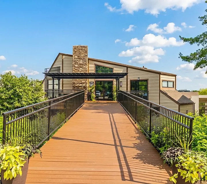Inviting contemporary apartment entrance with lush greenery and modern walkway leading to stylish building exterior at Creeks at Kirklevington Apartments in Lexington KY