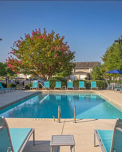 Inviting outdoor pool area with comfortable lounge chairs, vibrant greenery, and clear blue skies at Stratford at Hillcrest Apartments in Winston-Salem.