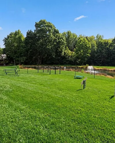 Charming outdoor space featuring lush green grass, pet-friendly amenities, and a scenic pond view, perfect for relaxation and leisure.