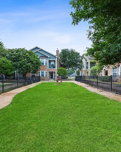 Charming apartment community with idyllic green space surrounded by modern brick buildings and lush trees, perfect for relaxation at Cottonwood Ridgeview Apartments in Plano TX