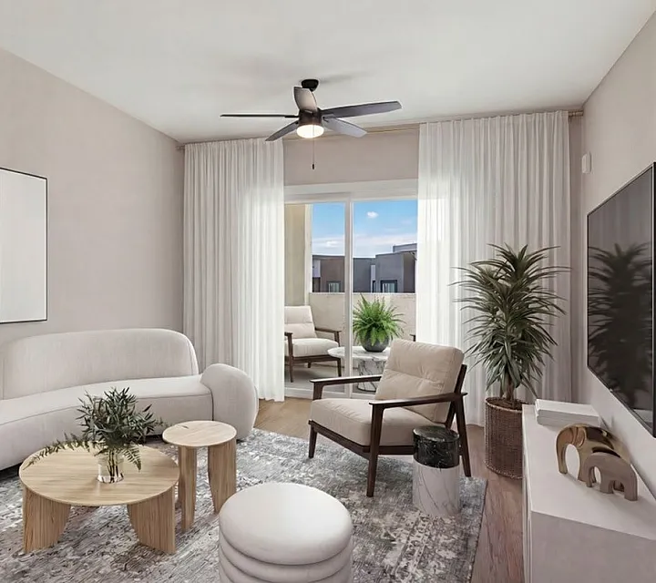 Modern living room with elegant white sofa, chic armchairs, and stylish decor, featuring a large window with natural light and a cozy balcony view at Summit On Boulder Apartments In Henderson NV