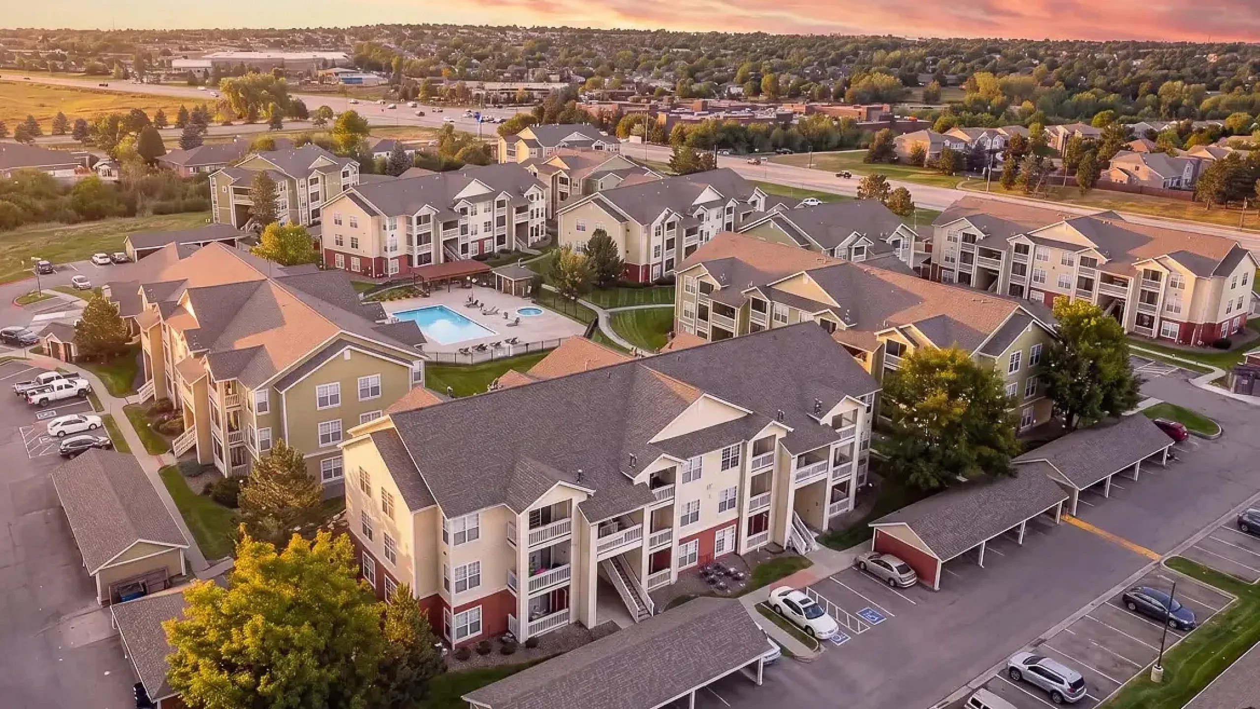 Charming apartment complex with lush landscaping and a central swimming pool, offering a serene and inviting living environment.