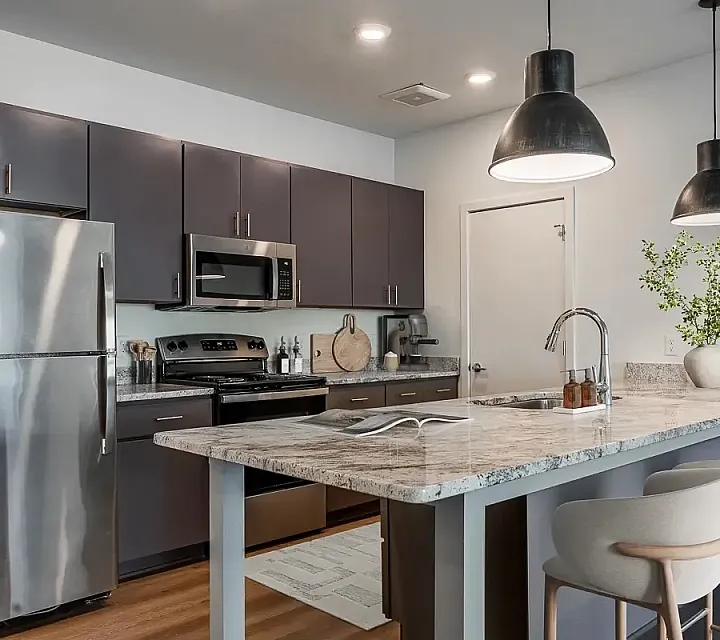 Contemporary kitchen with sleek appliances, elegant gray cabinetry, and a stylish marble island with pendant lighting.