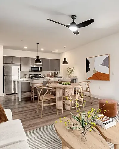 Bright and modern open-concept living space featuring a sleek kitchen with dark cabinetry, stylish dining area, and cozy living room with abundant natural light.