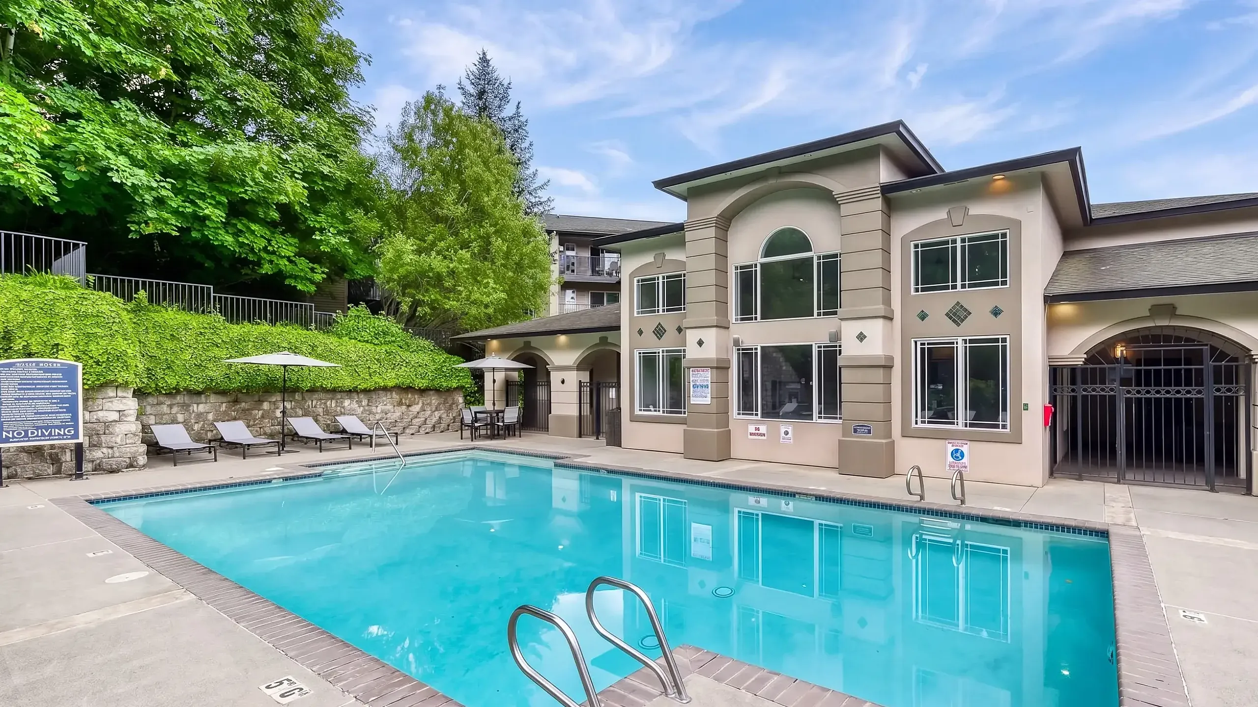 Inviting apartment complex with a sparkling outdoor pool, surrounded by elegant sun loungers and umbrellas for ultimate relaxation.