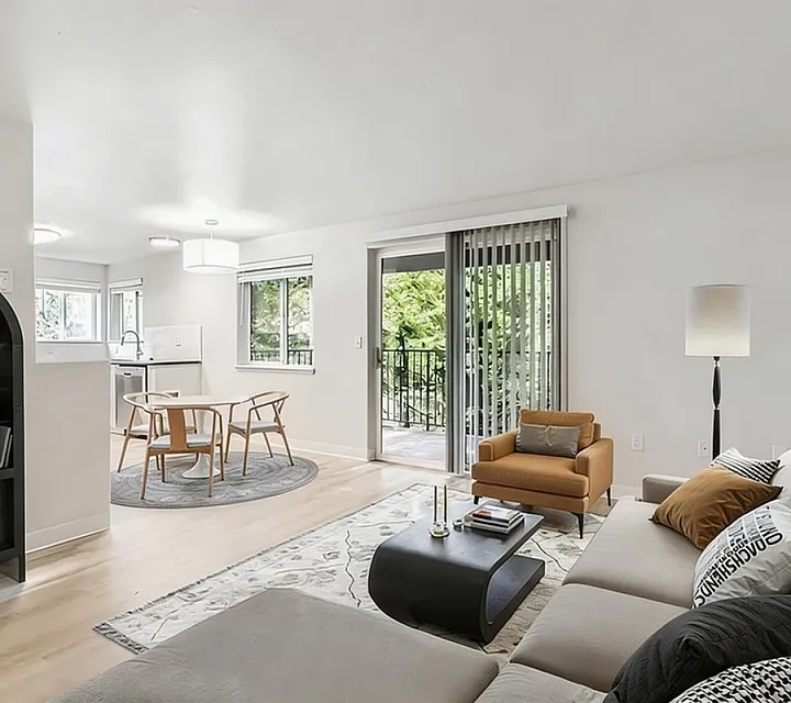 Bright and airy living room with modern decor, open-concept design, and sliding glass doors leading to a lush green view.