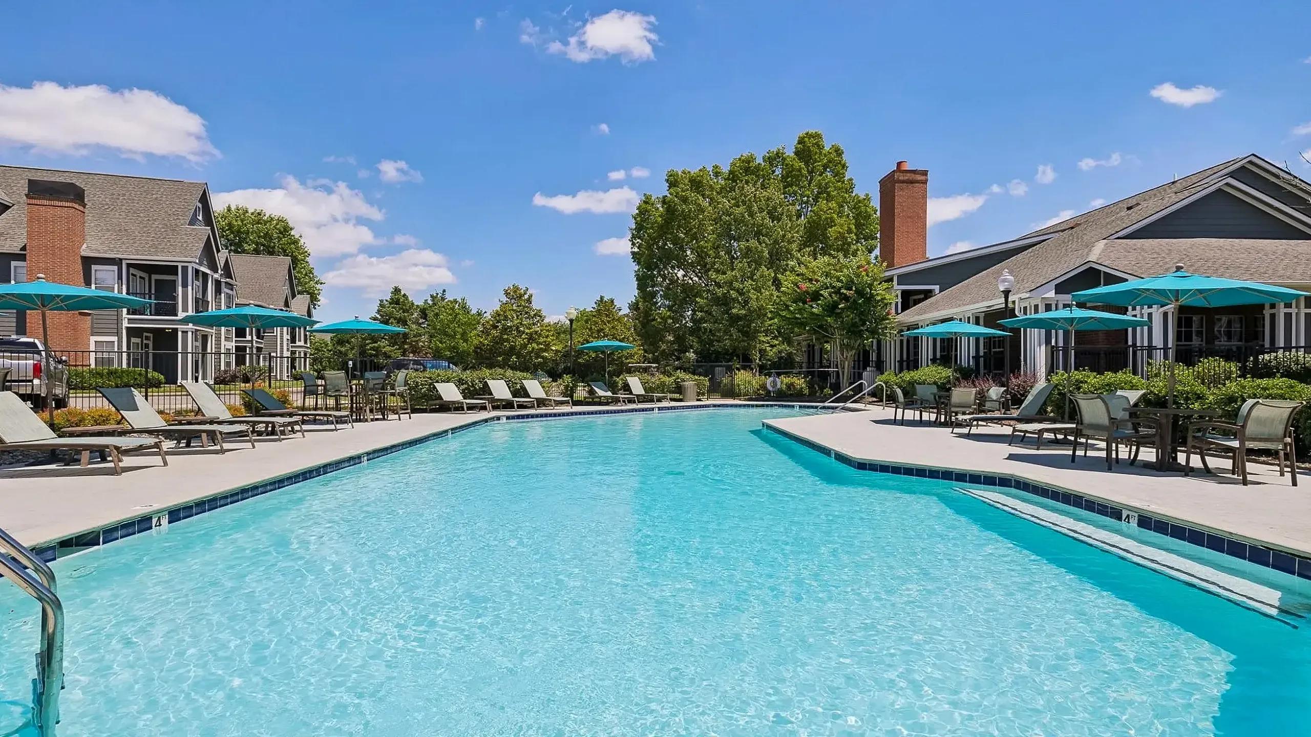 Luxurious apartment complex, Cason Estates Apartments, with serene poolside view at sunset, featuring inviting loungers and stylish blue umbrellas.