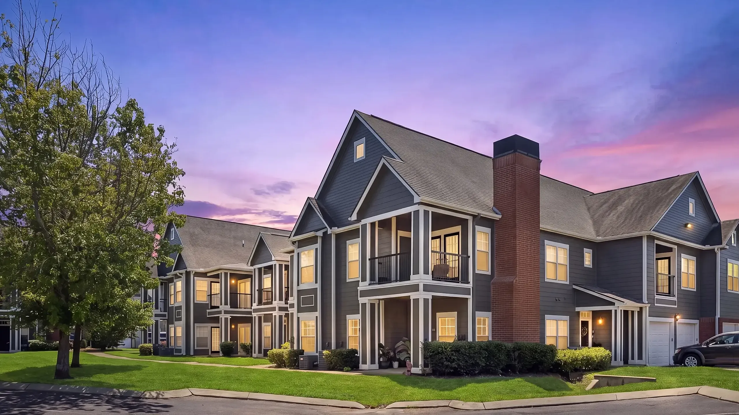 Charming two-story apartment complex with modern facade and inviting balconies, set against a breathtaking twilight sky.
