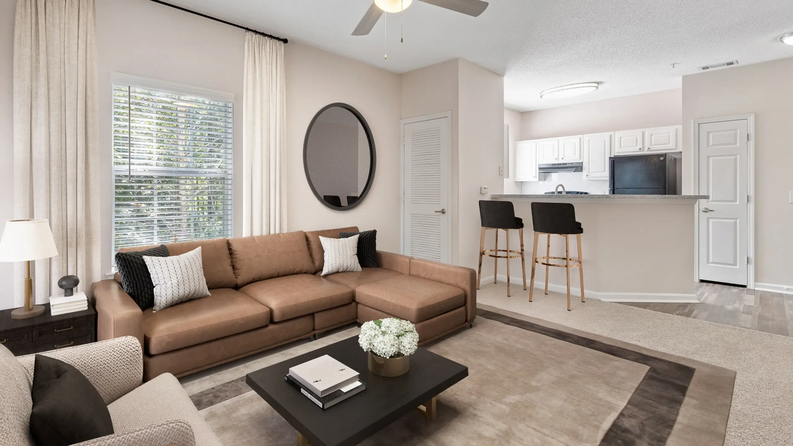 Modern living space at Summer Park Apartments with cozy brown sofa, sophisticated decor, and an inviting open-plan kitchen with bar seating.