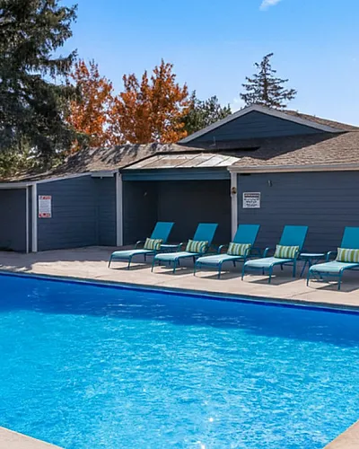 Inviting outdoor swimming pool area featuring vibrant blue sun loungers and a serene atmosphere, perfect for relaxation and leisure.