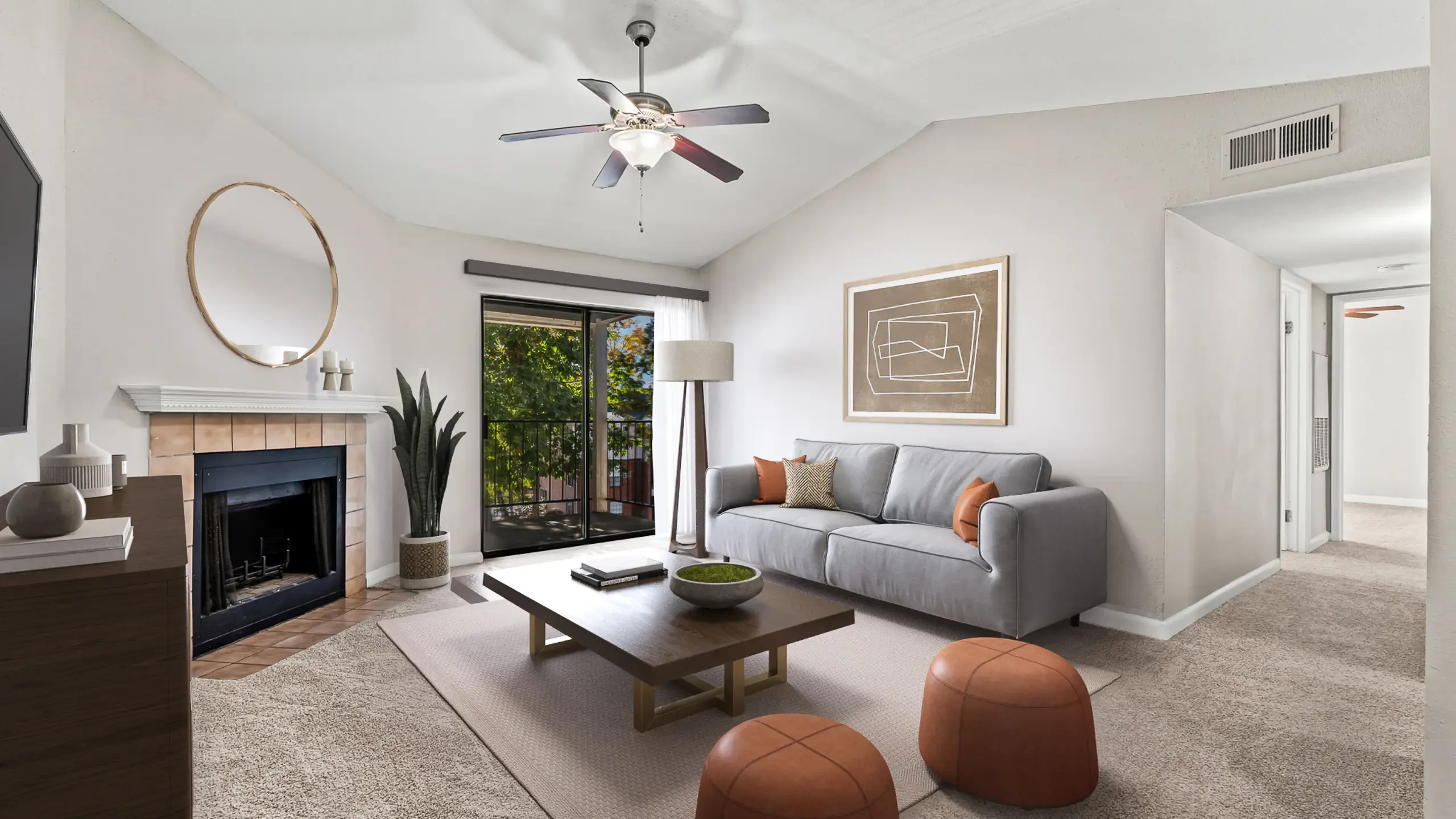 Bright living room with a modern gray sofa, cozy fireplace, and elegant decor, featuring large windows opening to a serene patio view at Autumn Ridge Apartments