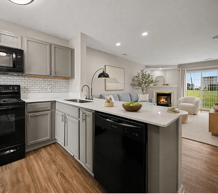 Chic open-concept kitchen and living area with elegant cabinetry, a cozy fireplace, and natural light pouring in through large windows at Alkire Glen Apartments.